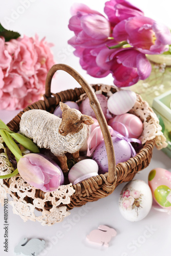 Easter wicker basket with lamb figurine and colorful eggs