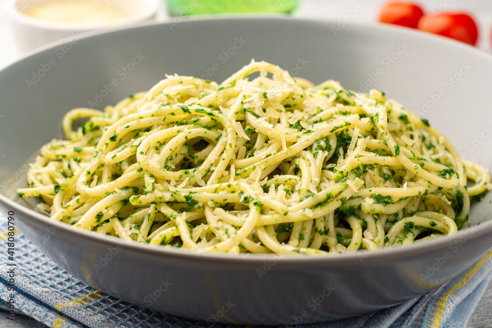Spaghetti pasta with spinach sauce and parmesan cheese on concrete background
