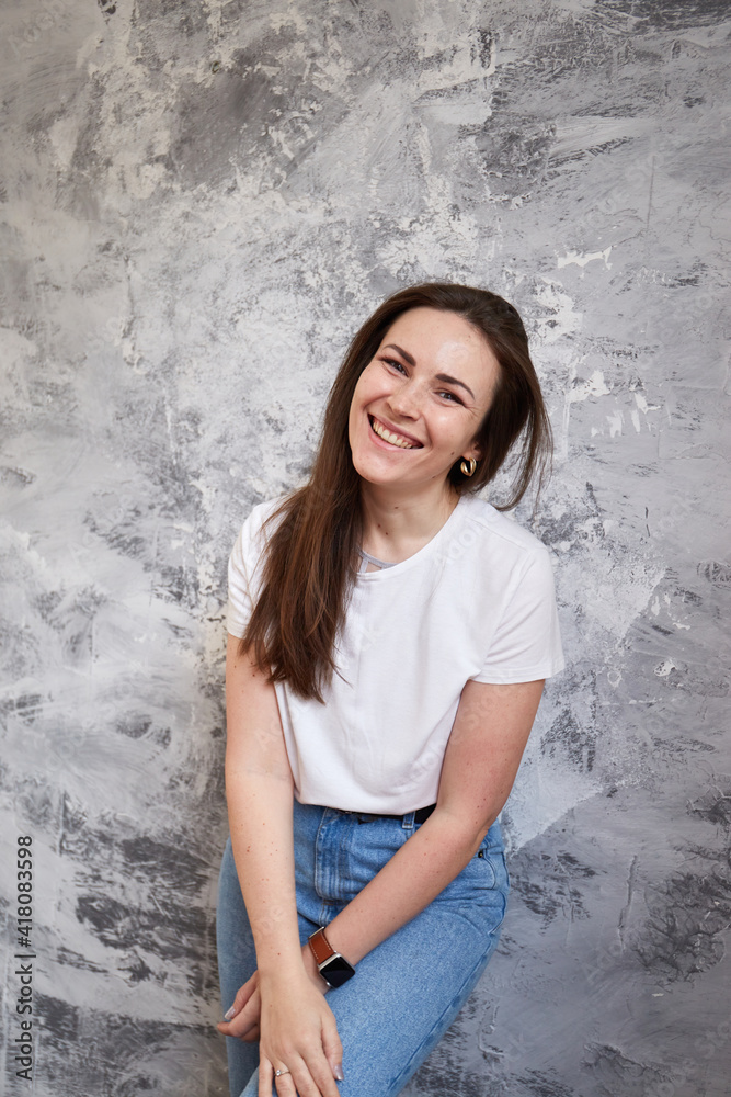 Smiling caucasian woman looking at the camera over gray background. Trendy clothes Smiling caucasian woman looking at the camera over gray background. Trendy clothes