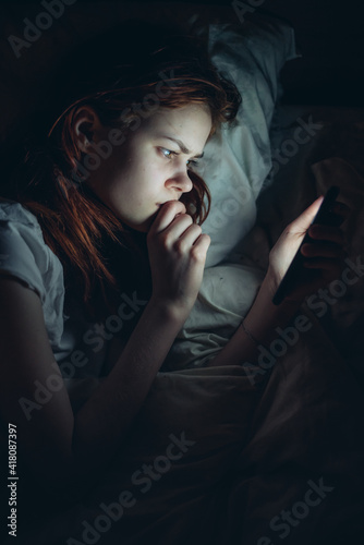 woman lies in bed with a phone in her hands emotions relaxation before bed communication