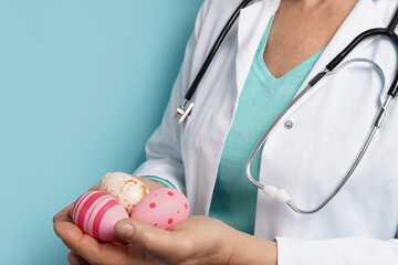 doctor with stethoscope holding Easter pink eggs on blue background