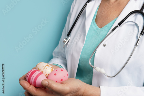 Canvas Print doctor with stethoscope holding Easter pink eggs on blue background