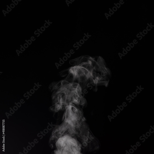 Curly white steam rising up and splashing water scattering in different directions isolated on a black background.