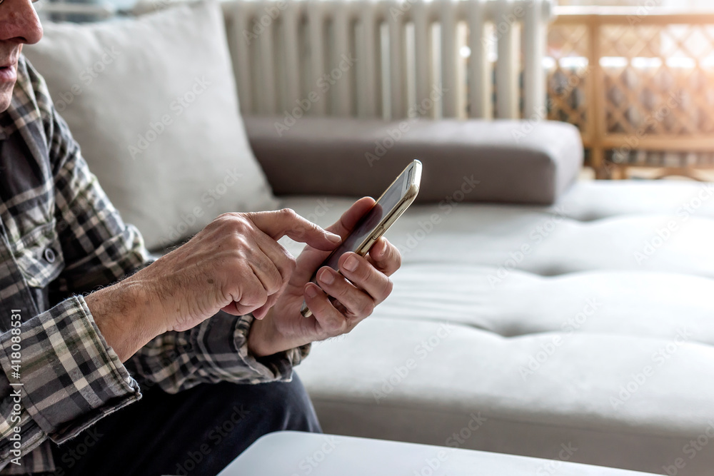Senior man sitting on bed and using mobile phone. Close up. Smiling old man text messaging on cell phone at home. Man sitting on sofa and holding a smartphone. Elderly man texting on smartphone. Senior man sitting on bed and using mobile phone. Close up. Smiling old man text messaging on cell phone at home. Man sitting on sofa and holding a smartphone. Elderly man texting on smartphone.