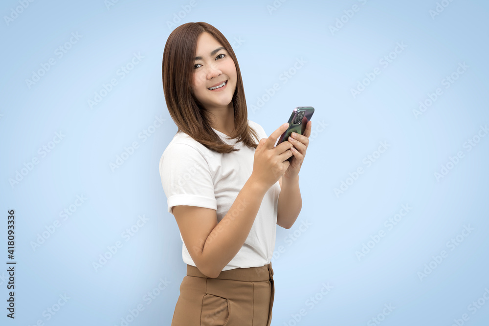 Beautiful Asian woman wearing white t-shirt holding smart phone isolated on blue background. with clipping paths. Beautiful Asian woman wearing white t-shirt holding smart phone isolated on blue background. with clipping paths.