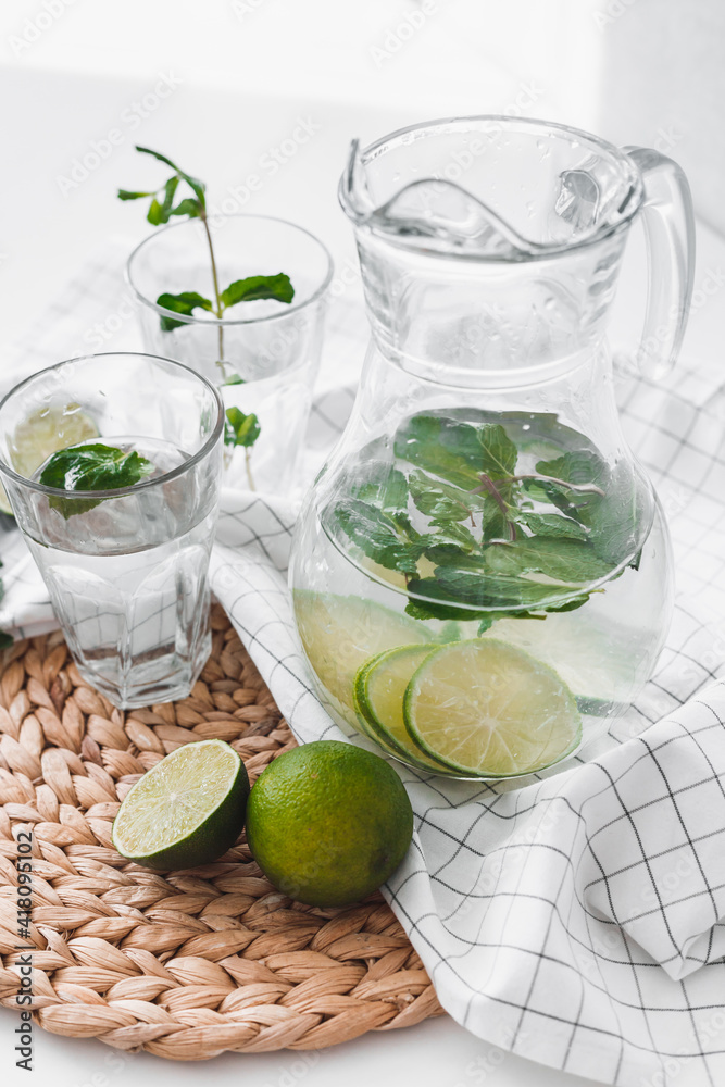 Detox water with lime fruit and mint leaves in jar and glasses Detox water with lime fruit and mint leaves in jar and glasses