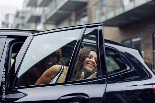Smiling woman in a swimwear getting out of a car with friends