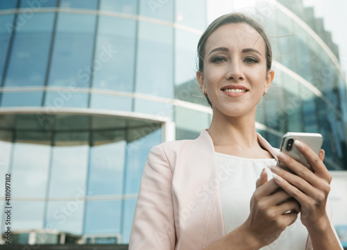 Executive working with a mobile phone in the street with office buildings in the background