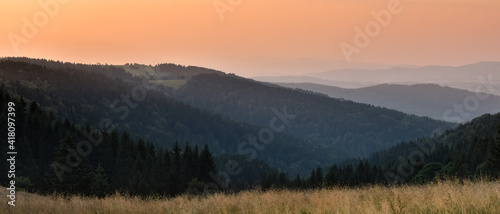 An orange sunset over a mountain range with a gentle fog in the valley.