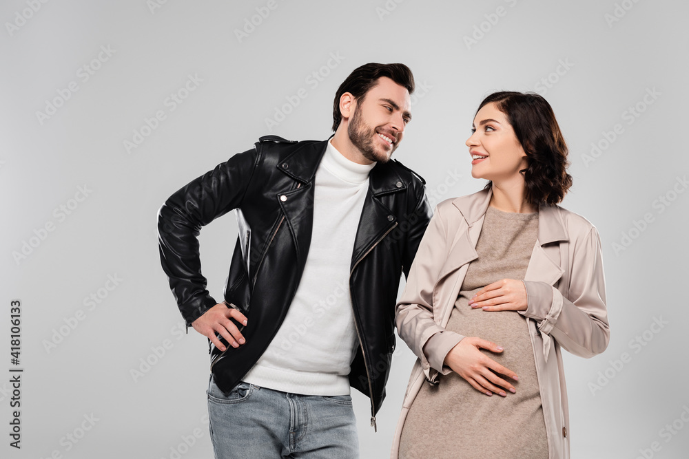 Pregnant woman smiling at husband isolated on grey