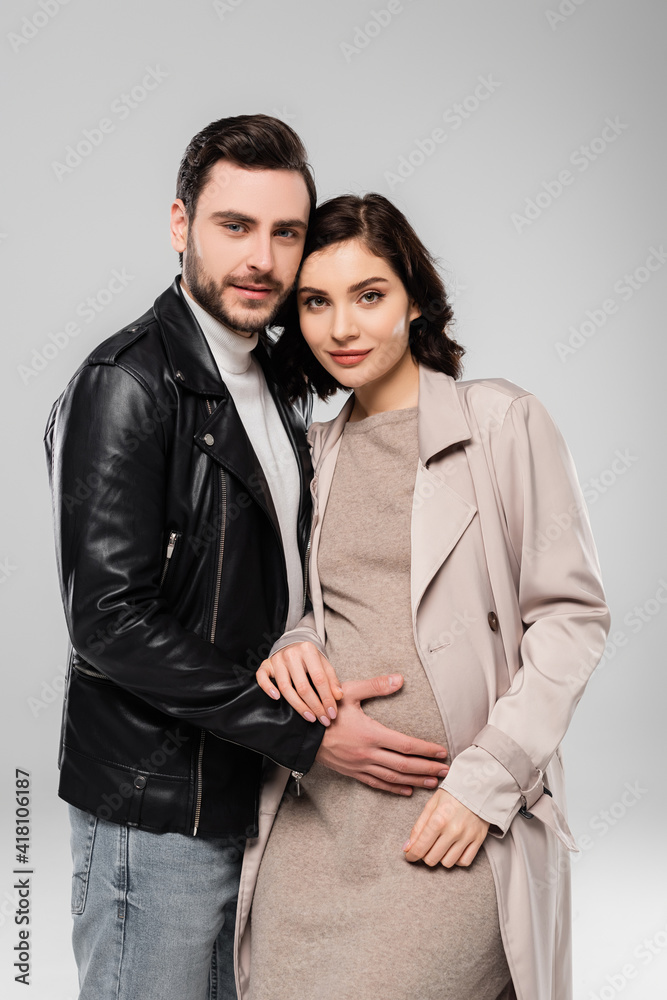 Stylish man standing near pregnant wife isolated on grey Stylish man standing near pregnant wife isolated on grey