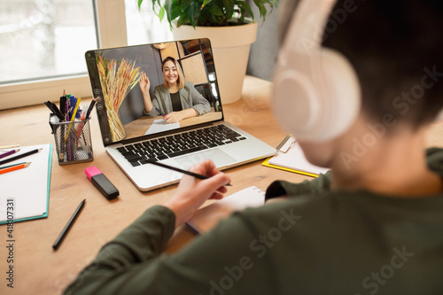 Little boy studying by group video call, use video conference with teacher, listening to online course. Using stationery, notebook. Easy, comfortable usage concept, education, online, childhood.