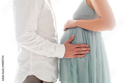 Cropped view of man in white shier touching belly of pregnant wife isolated on white