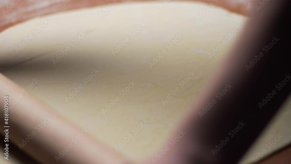 The chef prepares a delicious traditional Italian pizza dish and with the help of a kitchen tool rolling pin rolls out dough. Close up The chef prepares a delicious traditional Italian pizza dish and with the help of a kitchen tool rolling pin rolls out dough. Close up