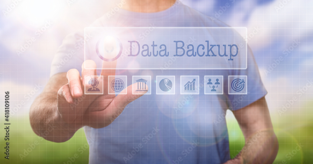 A man in a t-shirt outside selecting a Data Backup word concept on a computerised display A man in a t-shirt outside selecting a Data Backup word concept on a computerised display