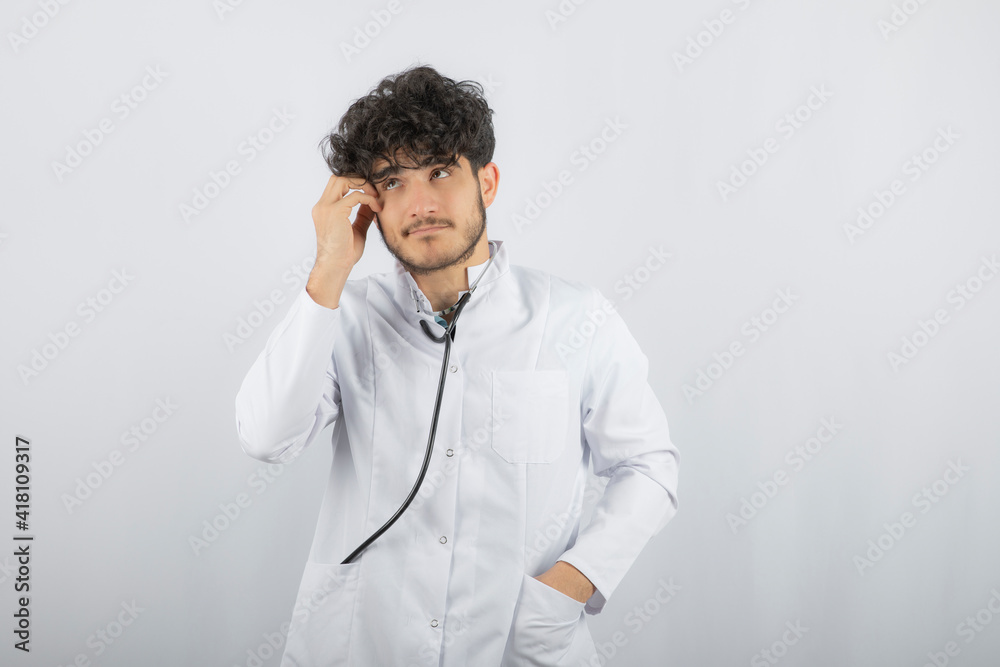 Thoughtful doctor holding his hand to his head and look up Thoughtful doctor holding his hand to his head and look up