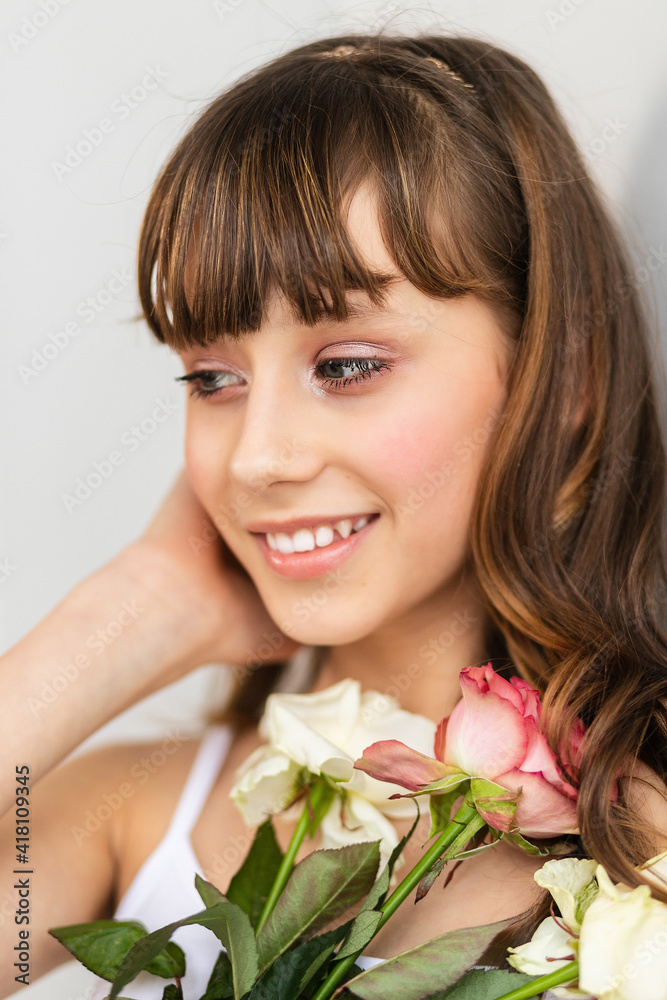 Little pretty girl in pink holds the bouquet of roses. Close up the flowers and face, little ballerina with a bouquet