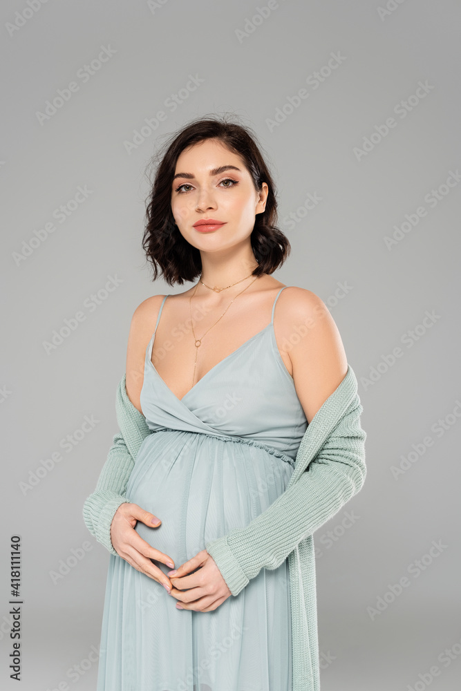 Pregnant woman in dress looking at camera isolated on grey Pregnant woman in dress looking at camera isolated on grey