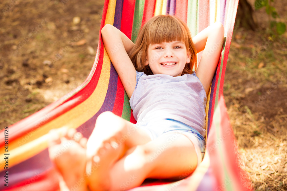 Summer vacation. Lovely child girl rest in colorful hammock outdoor in summer forest Summer vacation. Lovely child girl rest in colorful hammock outdoor in summer forest