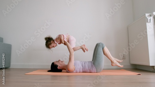 Mother lies and holds her little baby girl on hands at home