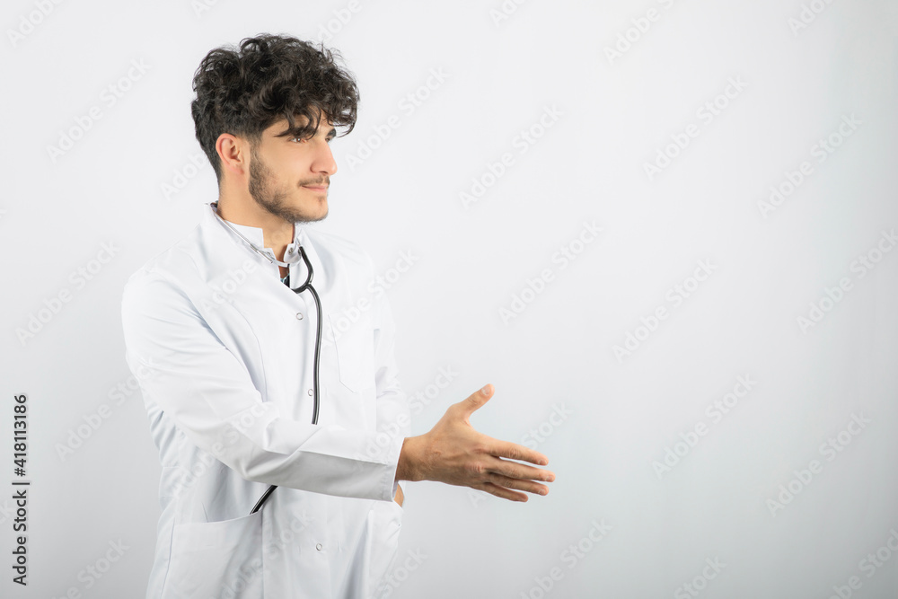 Smiling young doctor holding his hand up and try to shake hand Smiling young doctor holding his hand up and try to shake hand