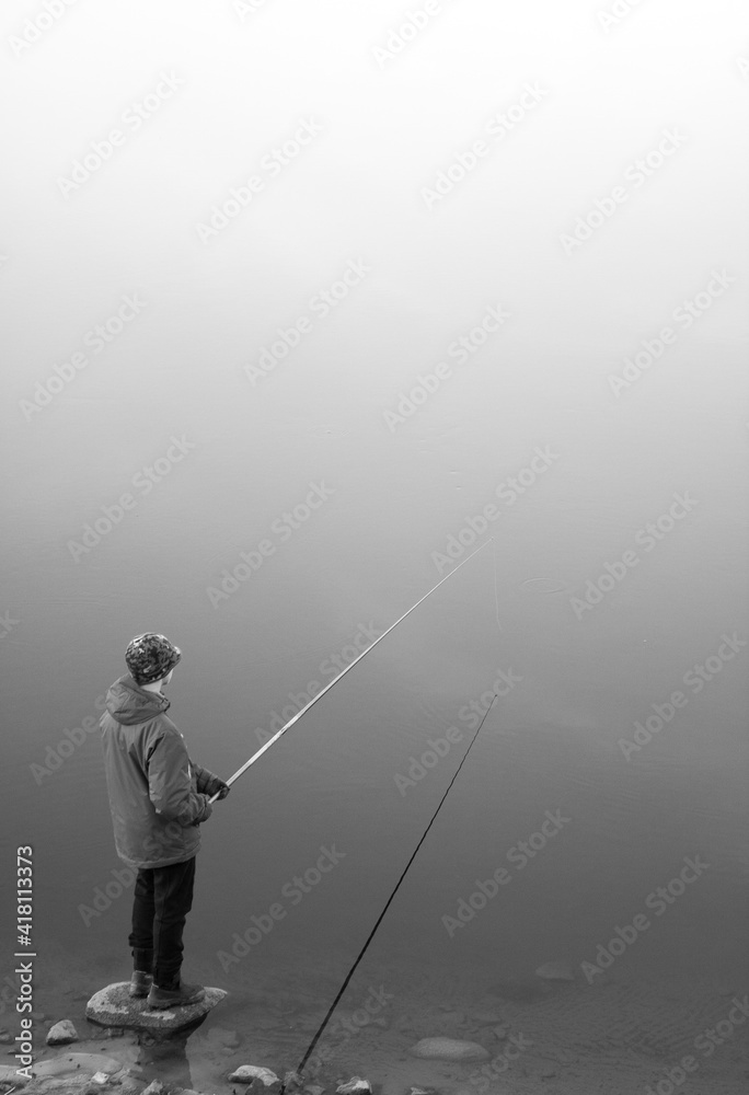 Meeting of a young fisherman on the lake in foggy weather. The atmosphere of calm and loneliness in black and white photography.