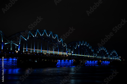 Illuminated railway bridge over Daugava river in Riga, Latvia. Night cityscape.