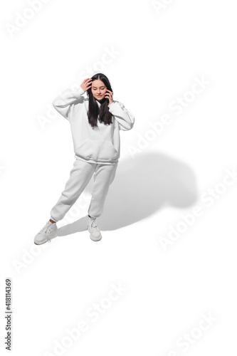 Talking phone. High angle view of young woman on white studio background. Girl in motion. Human emotions and facial expressions concept. Full length portait, copyspace for ad. Fashion, retro style.