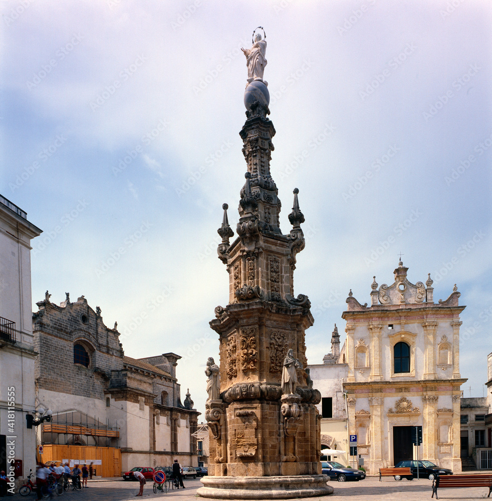 Nardò, Lecce. Guglia dell'Immacolata in Piazza Salandra con la chiesa di San Tritone.