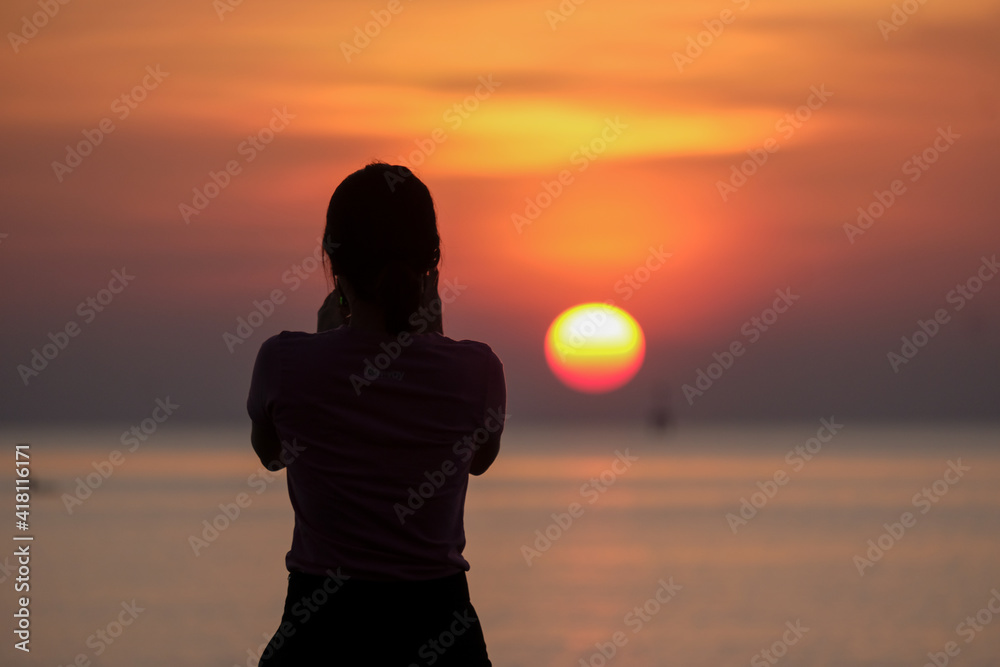 silhouette of beautiful thoughtful girl stand and enjoying the sunset, the figure of young woman on the beach, female meditate on nature