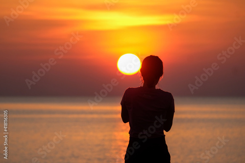 silhouette of beautiful thoughtful girl stand and enjoying the sunset, the figure of young woman on the beach, female meditate on nature