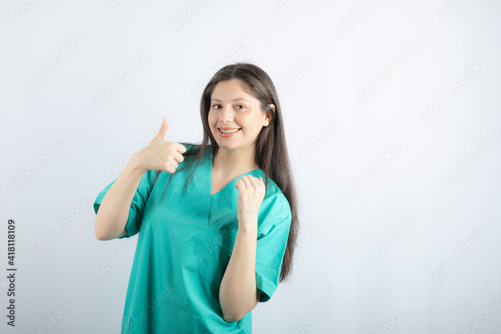 Smiling young beautiful nurse making thumb up on white background Smiling young beautiful nurse making thumb up on white background