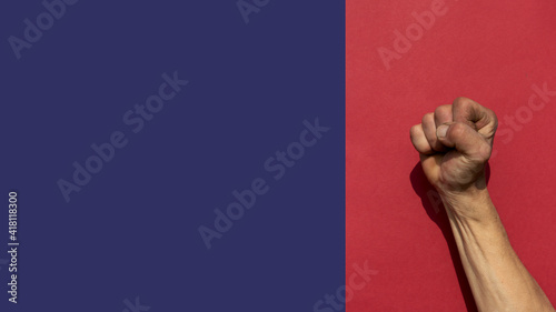 Swarthy rough mans hand with lenched fist on red background. Cesar Chavez Day concept.