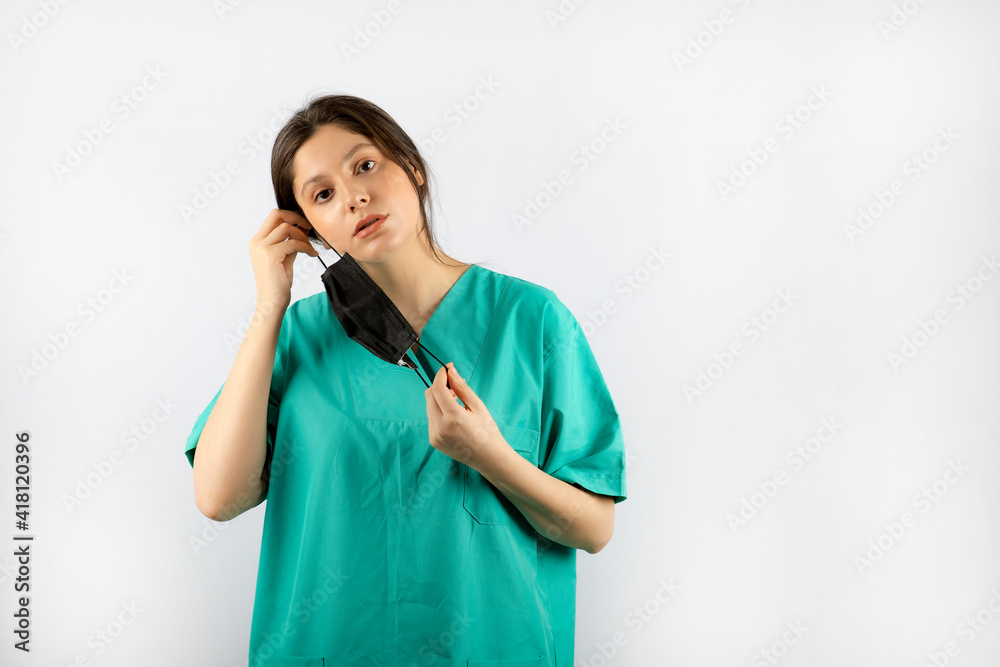 Young beautiful nurse taking off her mask while looking at camera Young beautiful nurse taking off her mask while looking at camera