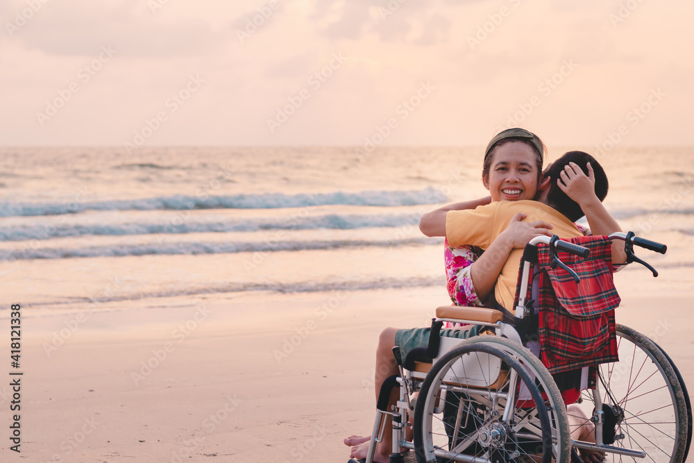 Mother and special child on wheelchair on the sea beach with sunset on travel time in holiday family, Learning about nature around the sea, Lifestyle in education age kids,Happy disabled kid concept..