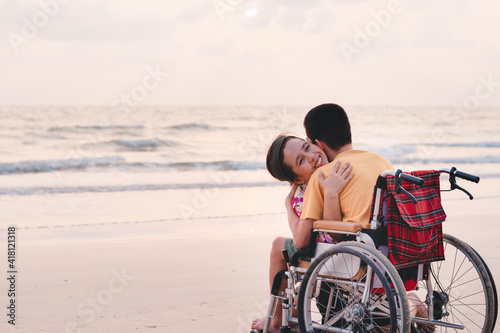 Mother and special child on wheelchair on the sea beach with sunset on travel time in holiday family, Learning about nature around the sea, Lifestyle in education age kids,Happy disabled kid concept..