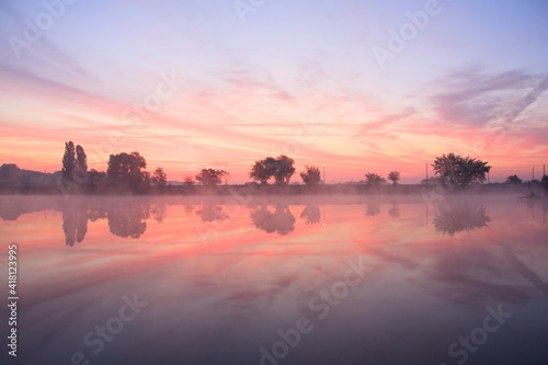 Pink foggy dawn on the misty lake