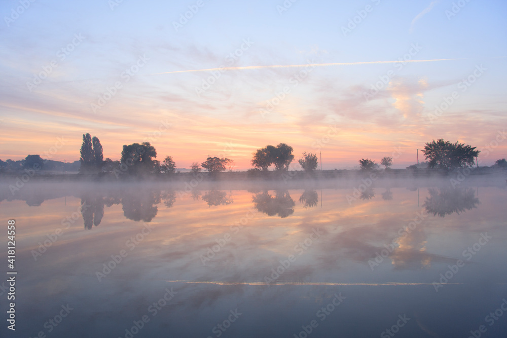 Pink foggy dawn on the  misty lake