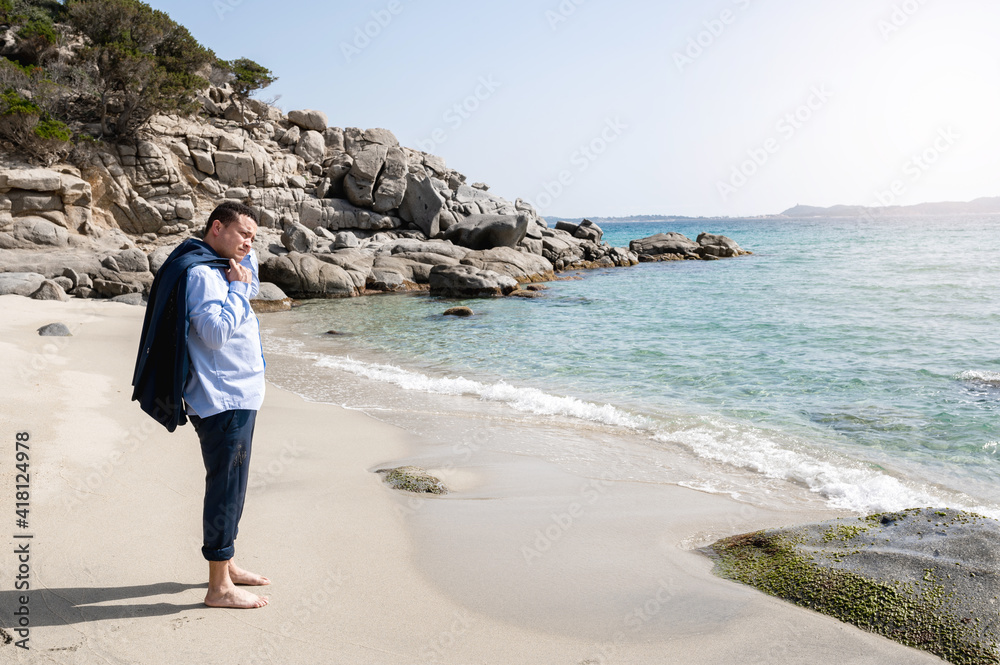 Latin businessman with suit take off jacket with barefoot standing on the shore in beautiful beach. Desire for freedom concept.