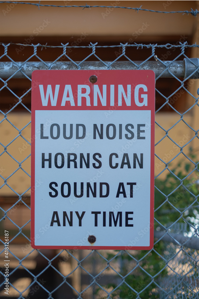 Sign warning loud noise horns can sound at any time on the fence at port. Sign warning loud noise horns can sound at any time on the fence at port.