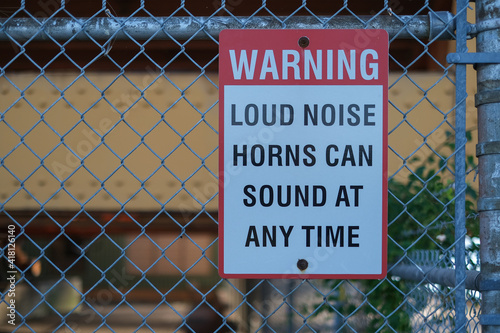 Sign warning loud noise horns can sound at any time on the fence at port.