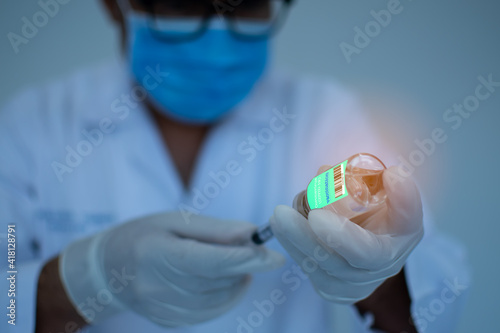 Photos A man wearing a mask holds a syringe and a vaccine bottle
