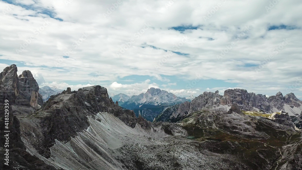 A panoramic view on Italian Dolomites. There are many high and sharp peak in front, with many landslides. Dangerous climbing. Barely any plants growing in the  area. Raw and unspoiled landscape.