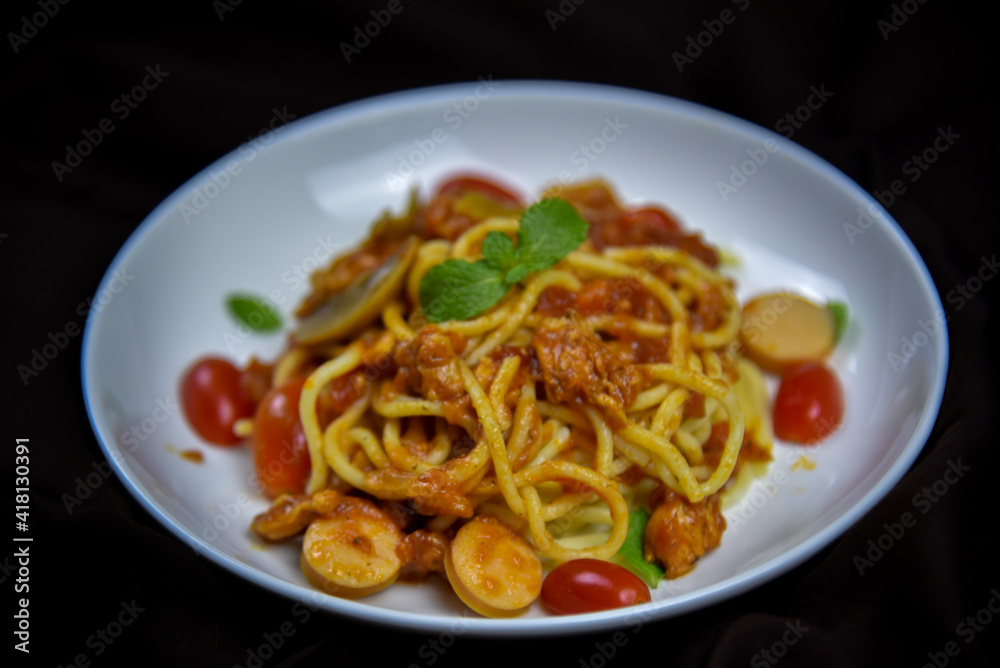 Delicious classic Italian spaghetti with tomato sauce, Parmesan cheese and mint leaves on a plate. There is a writing area.