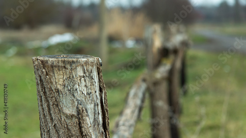 Column of an old farm fence against the backdrop of the countryside. Blurred background