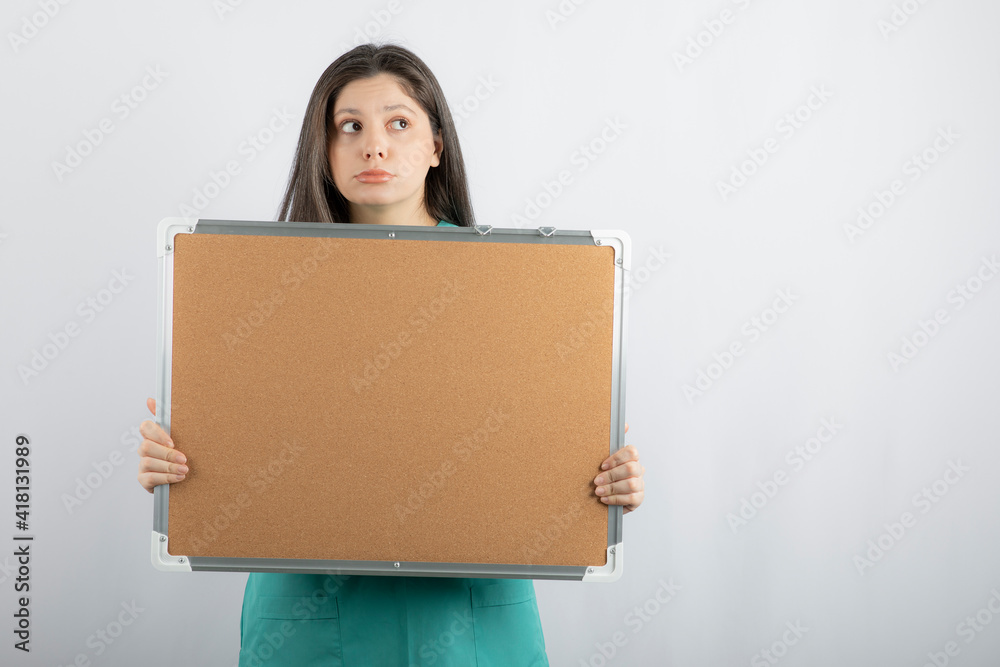 Thoughtful young nurse holding board with hand while looking away Thoughtful young nurse holding board with hand while looking away