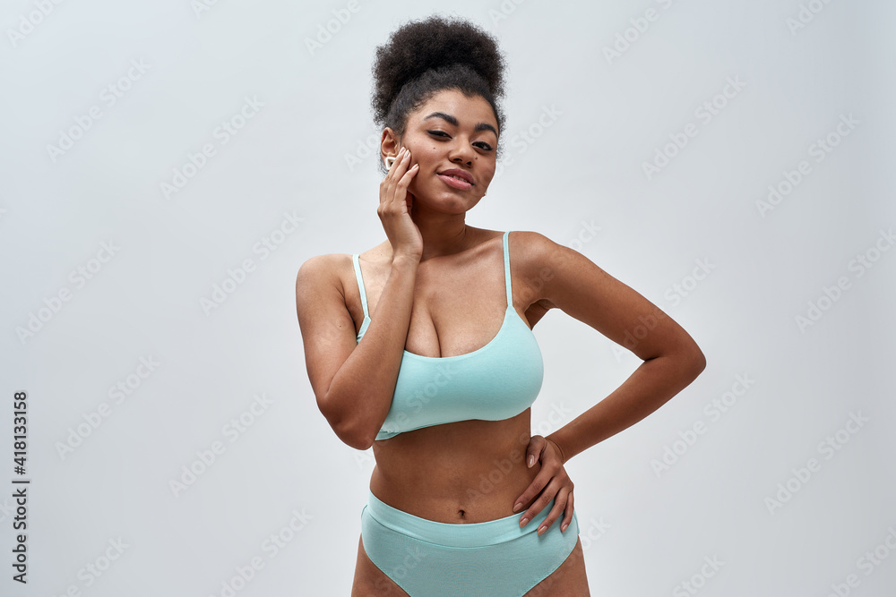 Beautiful sensual young mixed race woman wearing blue underwear posing for camera isolated over light background Beautiful sensual young mixed race woman wearing blue underwear posing for camera isolated over light background