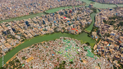 Aerial view of Karail district, a huge slum highly populated with houses made of tin roofs along  Banani lake with modern architecture skyline in background, Dhaka, Bangladesh. photo