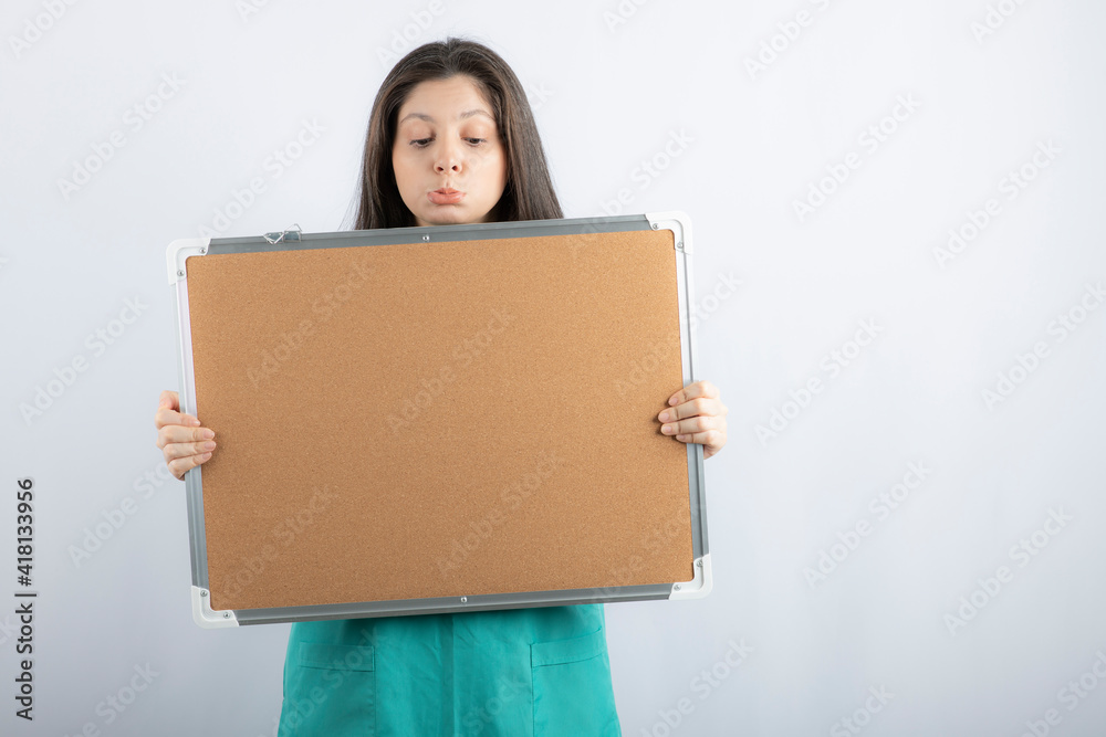 Upset young woman holding board and looking on it Upset young woman holding board and looking on it