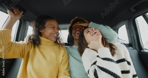 Diverse young female friends laughing
together in a car

